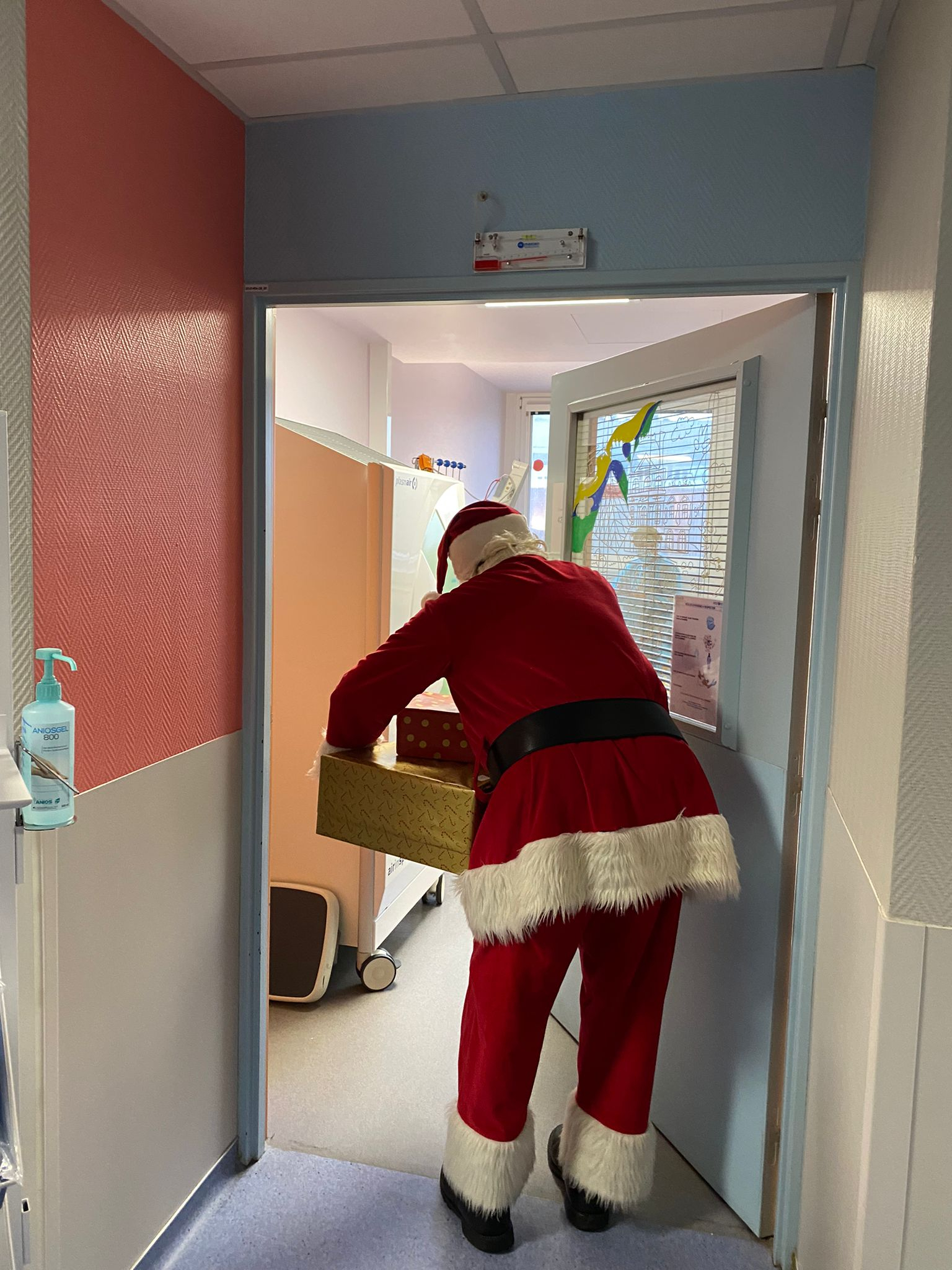 Le père Noël entrant dans une chambre d'enfant à l'hôpital Necker